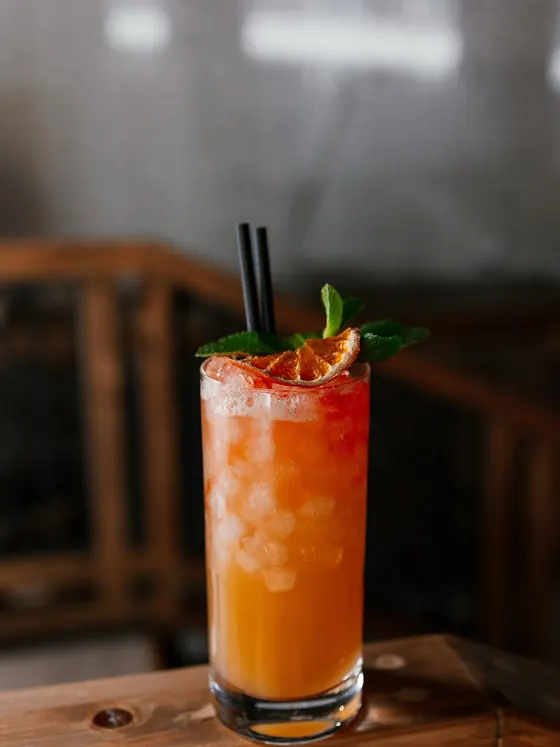 Orange cocktail with ice and mint in a tall glass