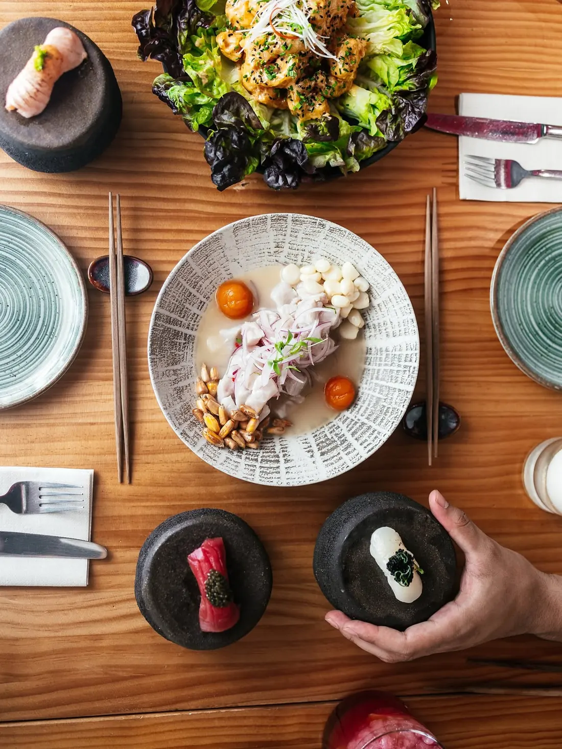 A table seen from above with ceviche, salad, nigiri and dishes to share