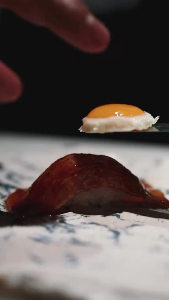 Un nigiri de wagyu sobre la tabla, con el huevo de codorniz a punto de coronarlo