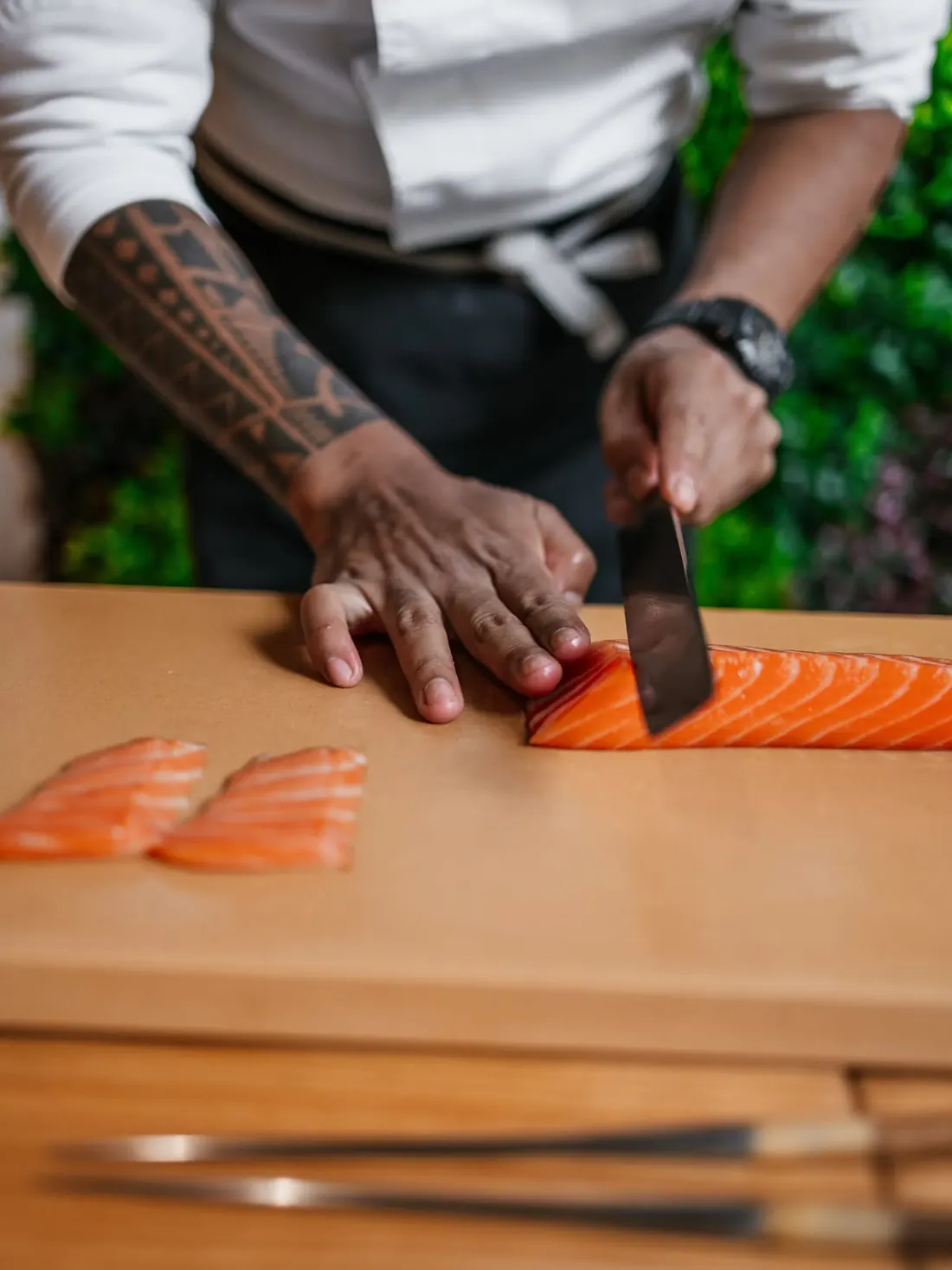 A cook slicing salmon on the wooden board