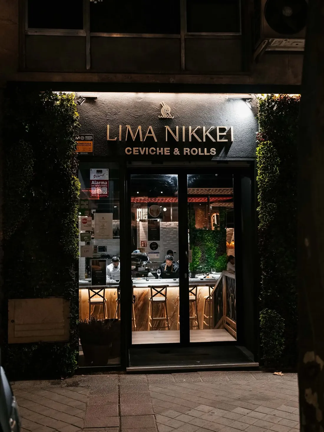 La entrada de Lima Nikkei de noche, con la barra iluminada al fondo