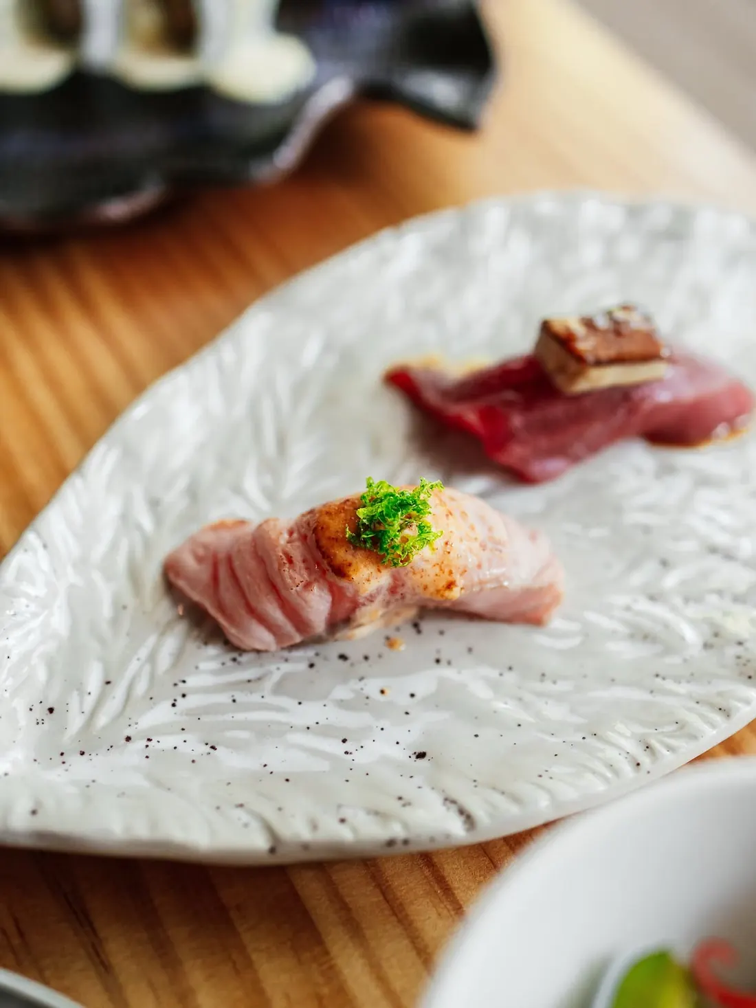 Tuna and white fish nigiri on a white ceramic plate