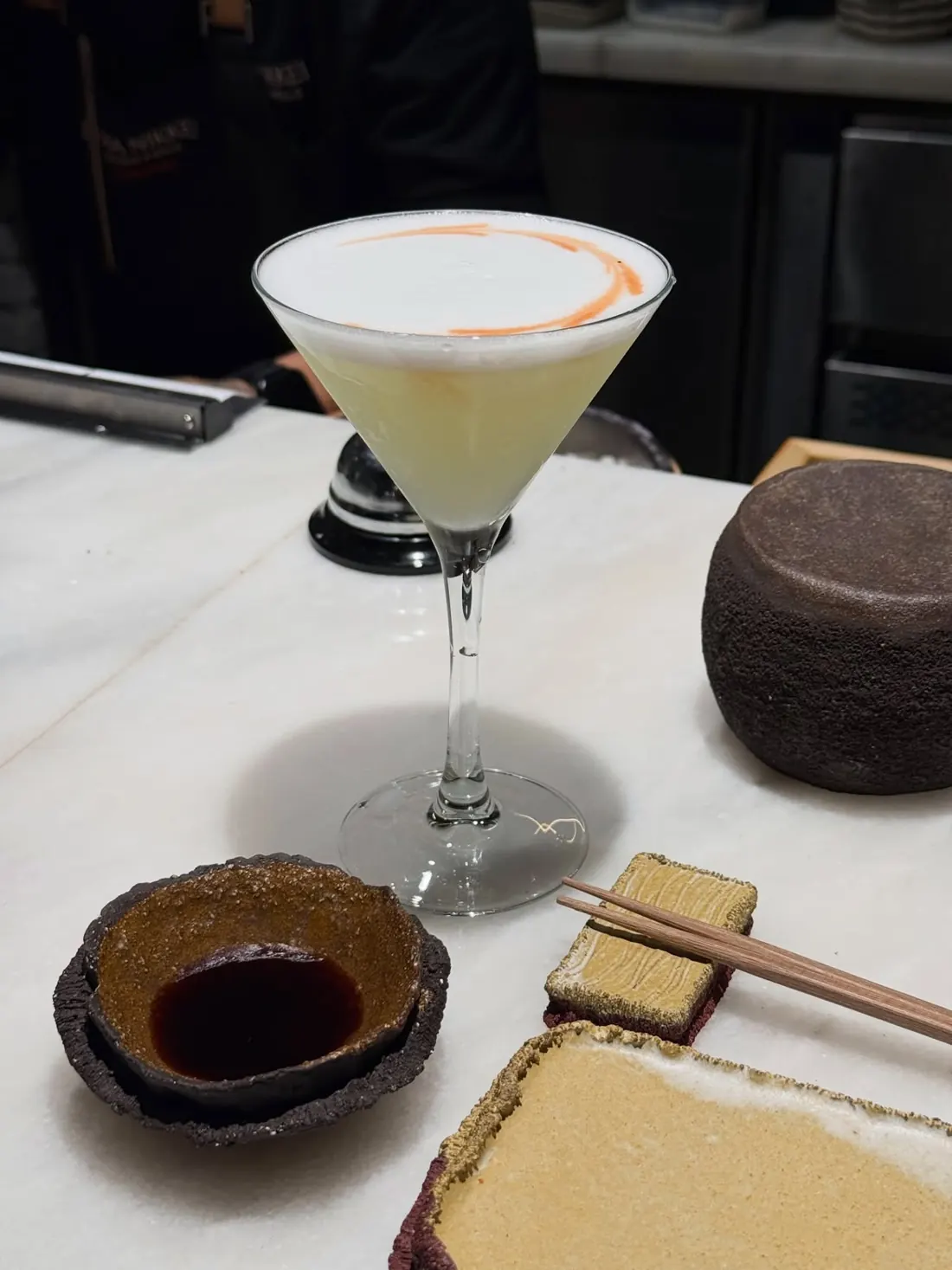 A pisco sour in a cocktail glass on the marble bar