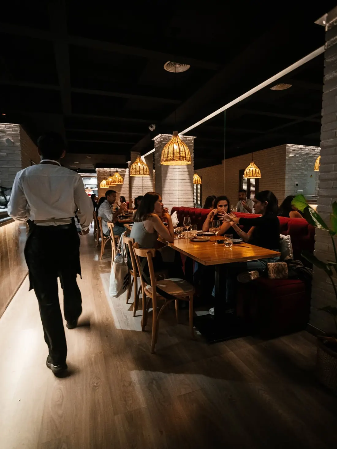 The Lima Nikkei dining room at night, with a waiter passing between busy tables