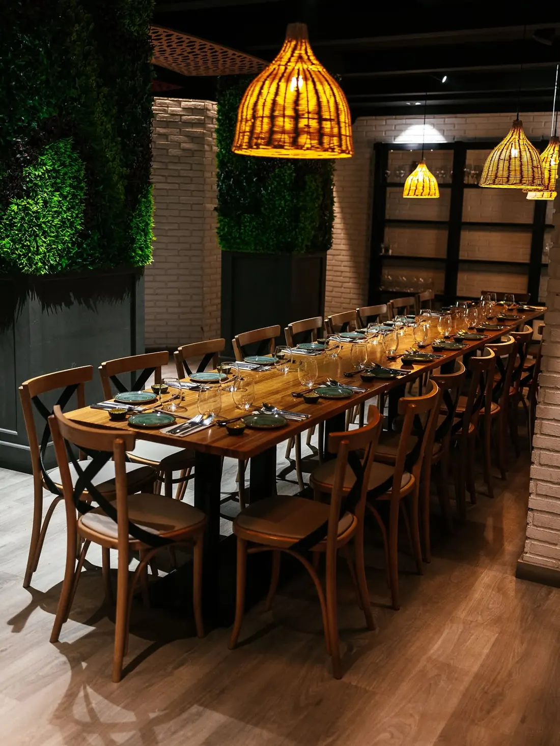 A long wooden table set under wicker lamps in the dining room