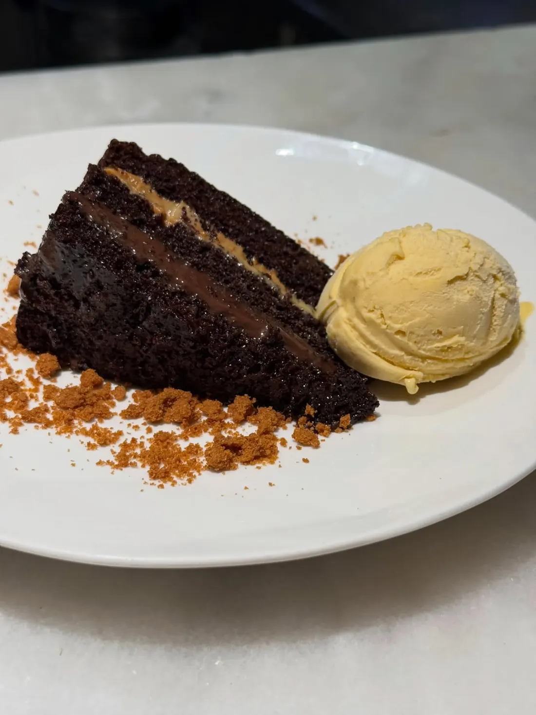 Layered chocolate cake with a scoop of ice cream and crumble