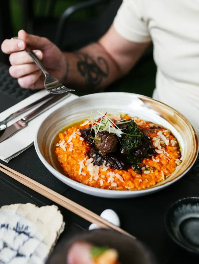 Arroz meloso con carne, salsa verde y brotes en Lima Nikkei